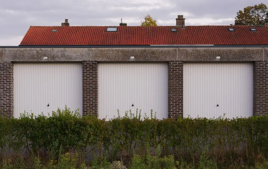 Row of older brick garages with white doors, typical of the detached garages found across Cornwall