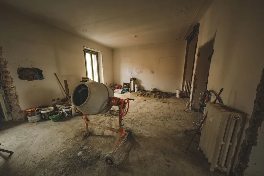 Stripped-out room with a bare concrete floor and cement mixer during a garage conversion in Cornwall