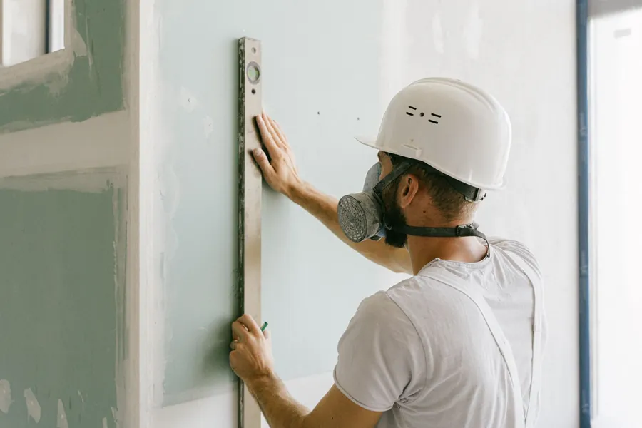 Insulated plasterboard being levelled against a wall during a Cornwall garage conversion