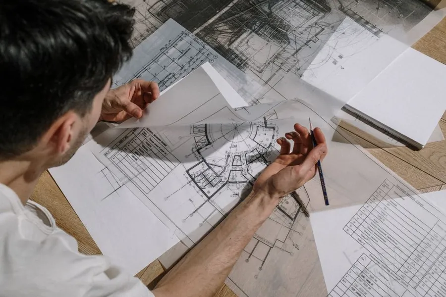 Hands reviewing architectural drawings for a granny annexe conversion, checking planning conditions before work starts