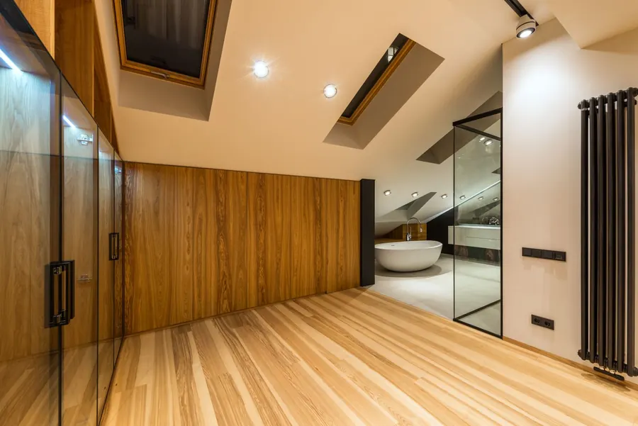 Converted loft with rooflights over a bath and a glass shower enclosure, the kind of bathroom a rear dormer added to a hip-to-gable loft conversion in Cornwall makes room for