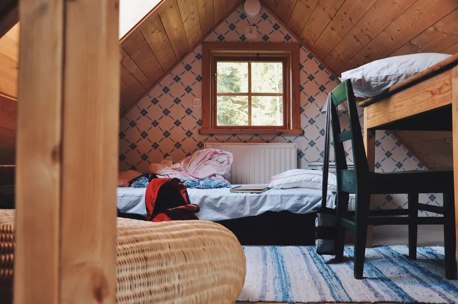 Small attic bedroom with a single bed, desk and gable window under timber-clad sloping ceilings, the kind of loft room a Falmouth student let has to measure against HMO space standards