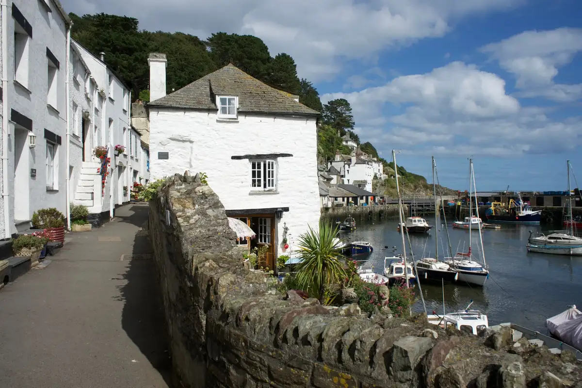Whitewashed cottages above a Cornish harbour, the kind of property where a garage or loft conversion is let to visitors