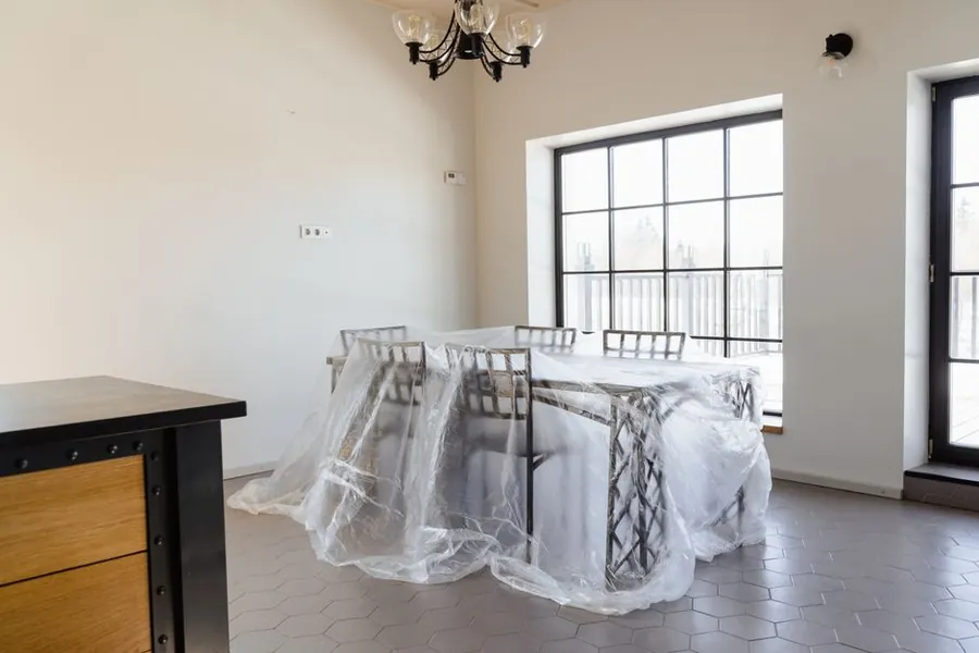 Furniture wrapped in protective sheeting during renovation work, containment that keeps the rest of the house usable