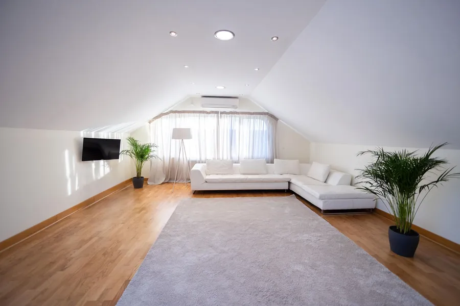 Finished loft conversion room with a sloping ceiling and full height space along the centre