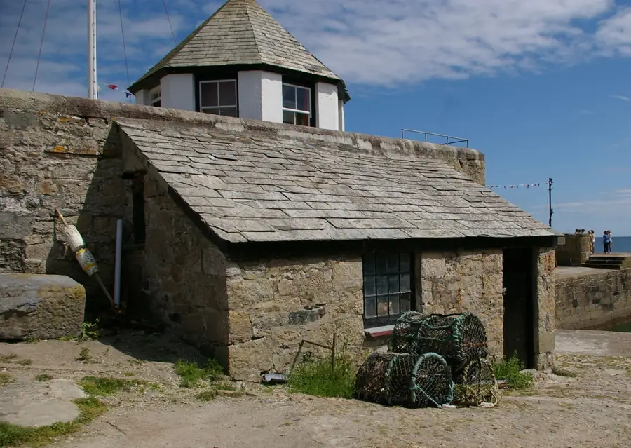 Slate roofed stone buildings on a Cornish harbour, typical of the roofscape protected inside Cornwall National Landscape