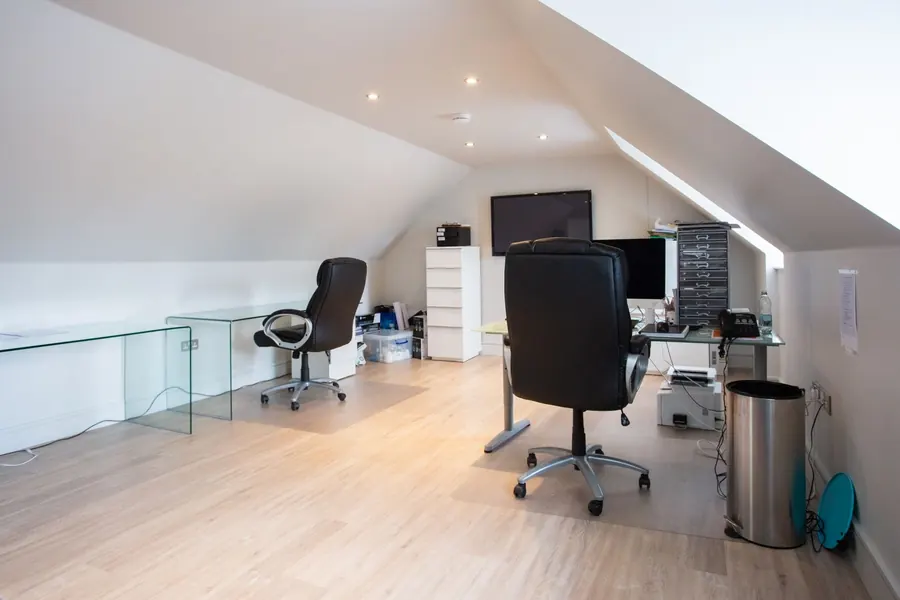 Finished loft conversion used as a home office with desks, recessed lighting and a sloping white ceiling, the result Truro and Falmouth homeowners are pricing for