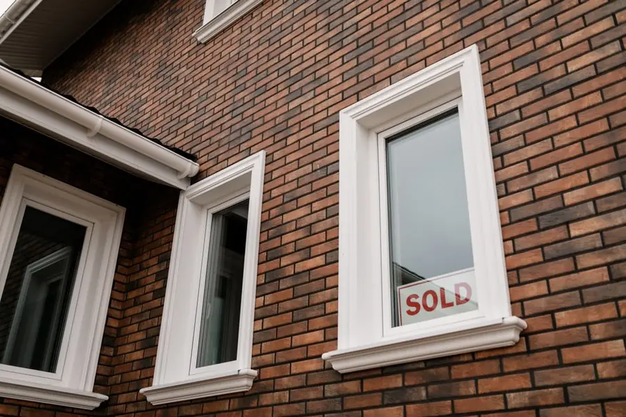 Sold sign in the window of a brick house, reflecting how an extra bedroom changes a property's sale bracket