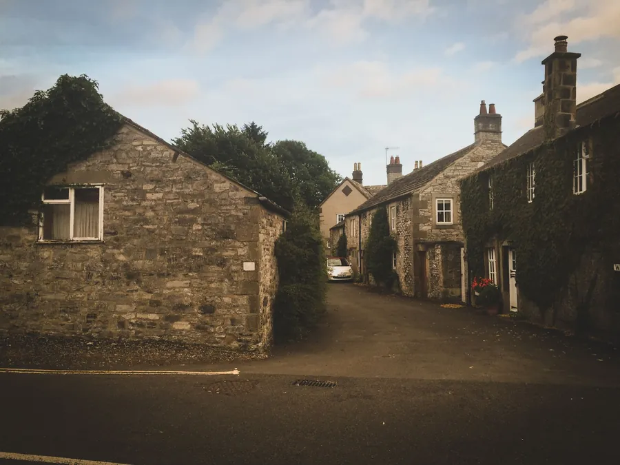 Narrow stone village lane with a car parked in it, the kind of Cornish street where off-street parking is worth keeping