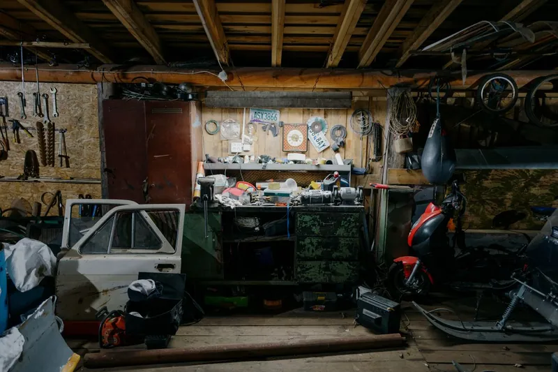 Inside a single-skin garage used for storage, with tools and household overflow against bare walls