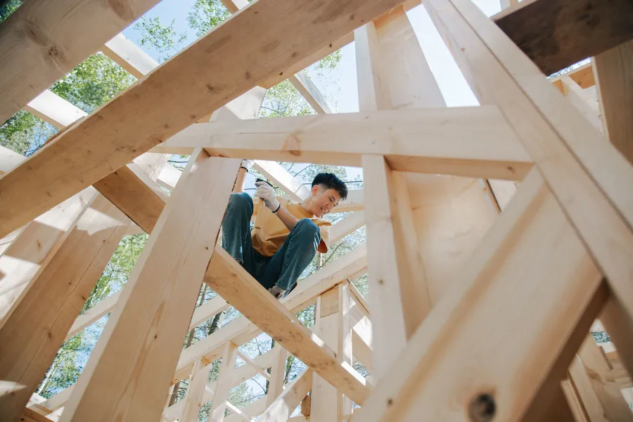 Carpenter working inside a new timber roof frame, the kind of rebuilt rafter structure that replaces the trusses in a Cornish loft conversion