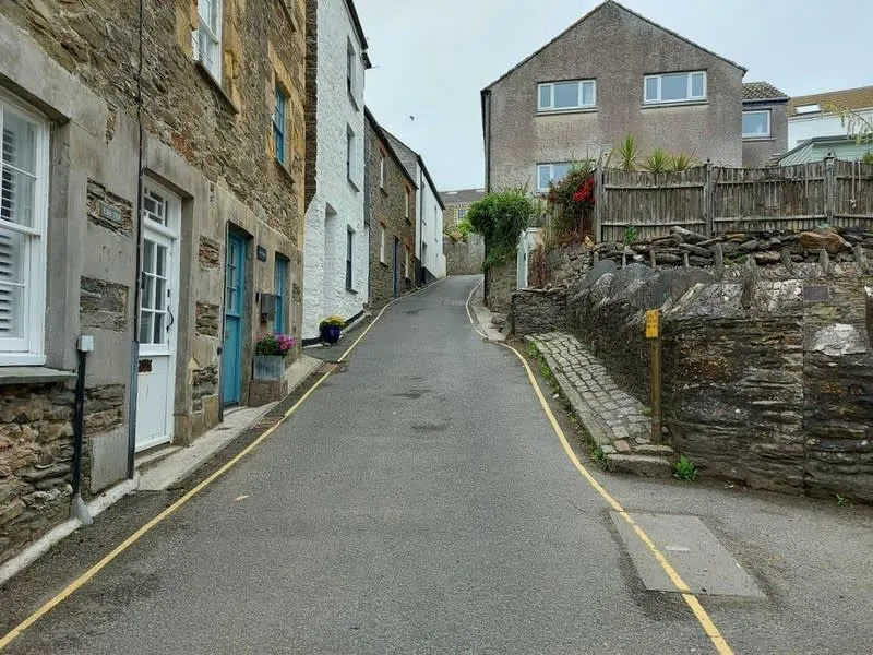 Narrow Cornish village street with stone cottages and restricted access for building work