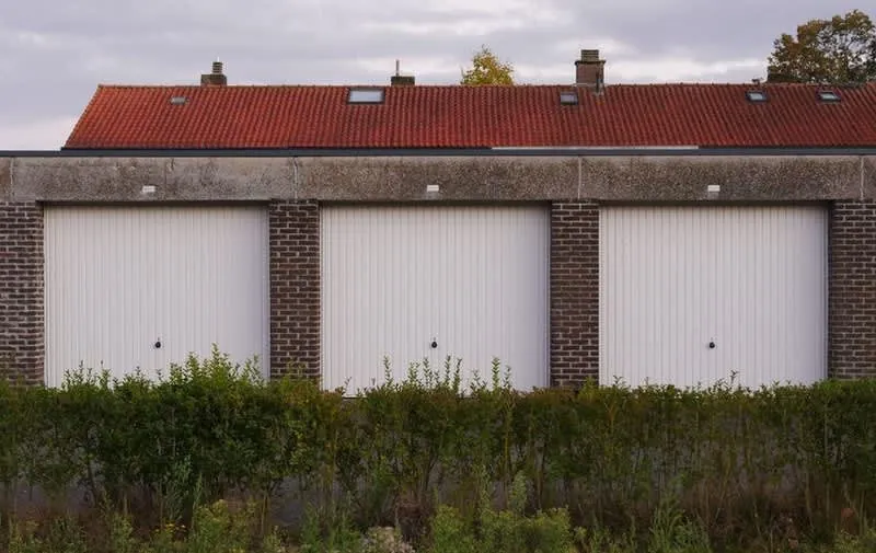 Row of detached brick garages with white doors, candidates for conversion to annexe accommodation in Cornwall