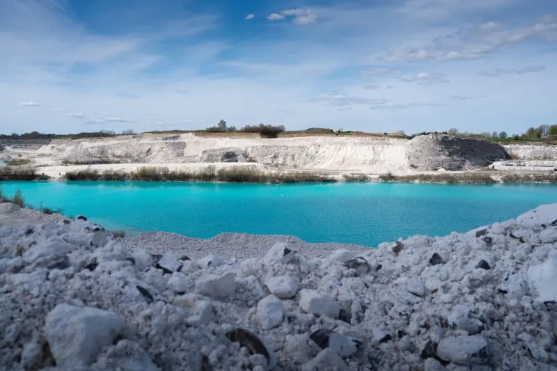Turquoise pool and white spoil inside a flooded clay pit