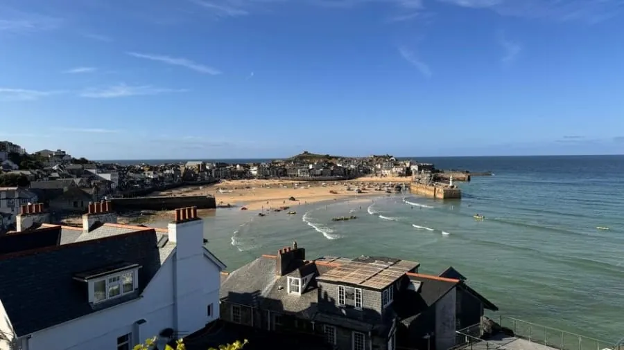Slate roofs with a small dormer window stepping down towards a harbour on the Cornish coast, the kind of town-centre housing a loft conversion in Truro or Falmouth deals with