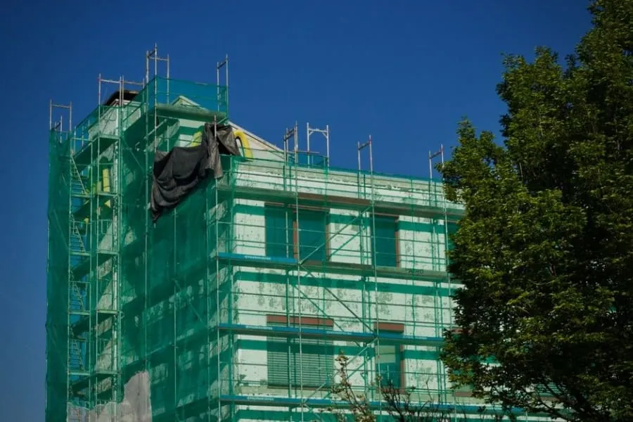 House wrapped in scaffolding and safety netting with the roof opened up, the stage a hip-to-gable loft conversion in Cornwall reaches when the sloping end comes off