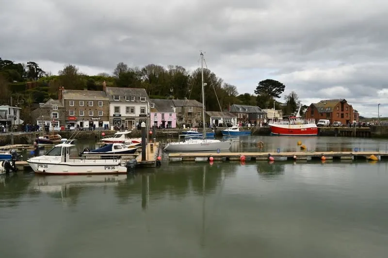 Padstow's working harbour with fishing boats, pontoons and the town climbing the hillside behind
