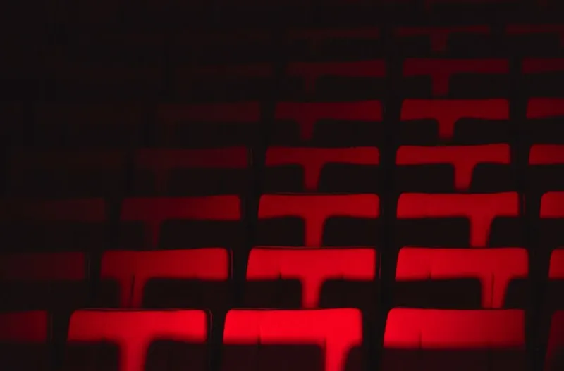 Rows of red theatre seats picked out by low auditorium lighting